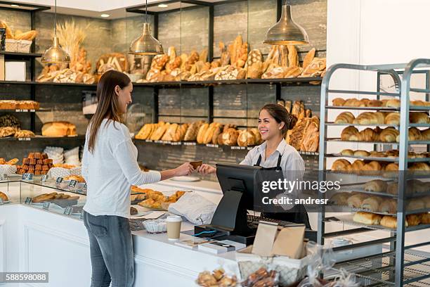 woman paying by card at the bakery - bakery stock pictures, royalty-free photos & images