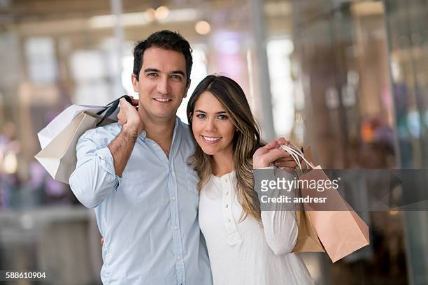 latin american couple shopping at the mall - latin american and hispanic shopping bags stockfoto's en -beelden