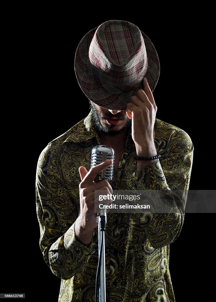 Retrato de un hombre hipster cantando mientras tocaba su sombrero