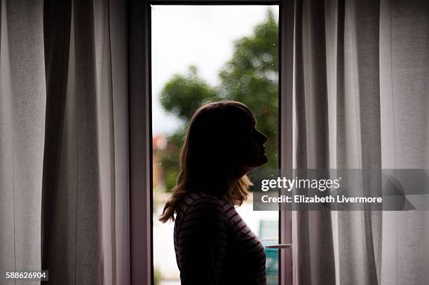 woman standing in profile by window - profile silhouette stock pictures, royalty-free photos & images