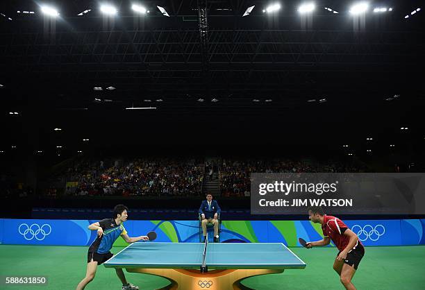 Japan's Jun Mizutani hits a shot against Belarus' Vladimir Samsonov in their men's singles bronze medal table tennis match at the Riocentro venue...