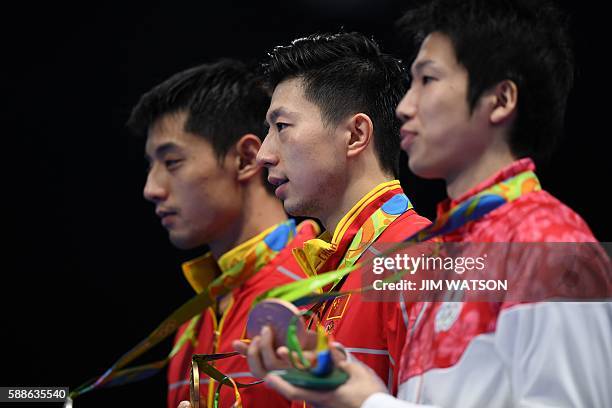 China's Zhang Jike poses with his silver medal, China's Ma Long poses with his gold medal, and Japan's Jun Mizutani poses with his bronze medal after...