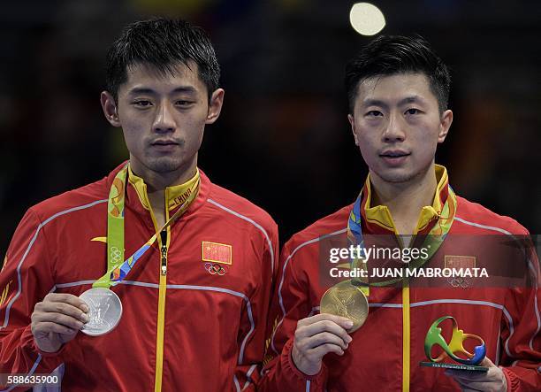 China's Zhang Jike poses with his silver medal and China's Ma Long poses with his gold medal after the final men's singles table tennis match at the...