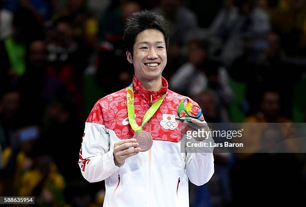 Bronze medalist Jun Mizutani of Japan poses on the podium during the medal ceremony for the Mens Table Tennis Gold Medal match between Ma Long of...