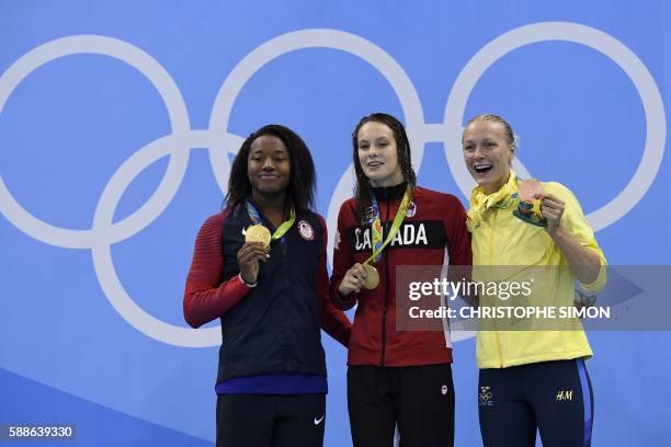 Gold medallists USA's Simone Manuel and Canada's Penny Oleksiak pose with bronze medallist Sweden's Sarah Sjostrom on the podium of the Women's 100m...