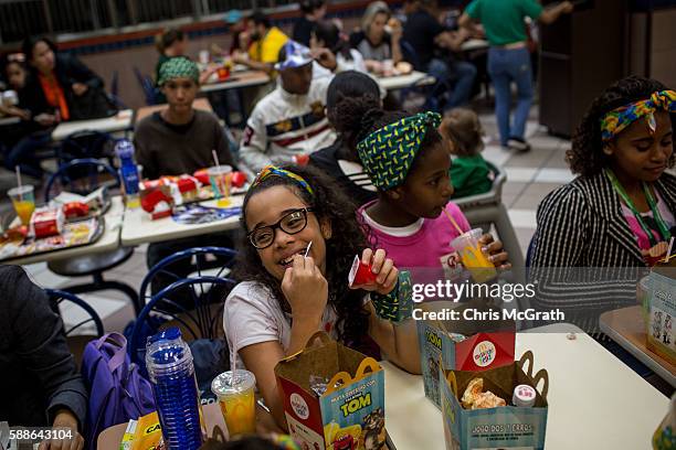 Julia Muniz from the Cantagalo 'favela' community enjoys a happy meal at McDonalds before heading to the Olympic Rugby 7's on August 11, 2016 in Rio...