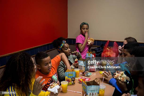 Children from the Cantagalo 'favela' community enjoy happy meals at McDonalds before heading to the Olympic Rugby 7's on August 11, 2016 in Rio de...