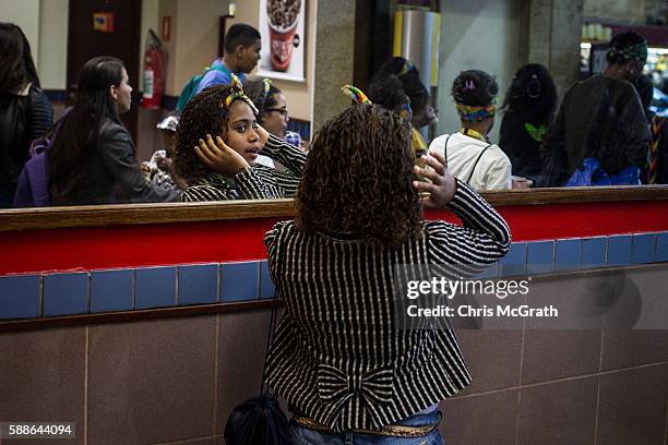 Kauany Santos from the Cantagalo 'favela' community fixes her hair in the mirror of a McDonald's store before leaving to watch the Olympic Rugby 7's...