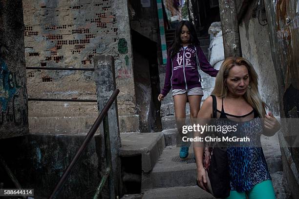 Julia Cristina Fretas Rocha and mother Marcia walk down stairs from their house in the Cantagalo 'favela' community to go to the Olympics on August...