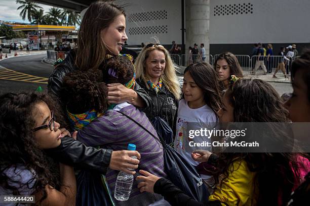 Kids from the Cantagalo "favela" community rush to hug Caminhos Manager Nadine Leptich thanking her for the Olympic tickets outside the Olympic rugby...