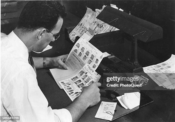 An FBI fingerprint expert attempts to make an identification with documents, Washington DC, 1950.