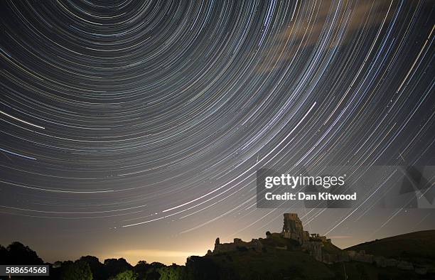 Satellites, planes and comets transit across the night sky under stars that appear to rotate above Corfe Castle on August 12, 2016 in Corfe Castle,...