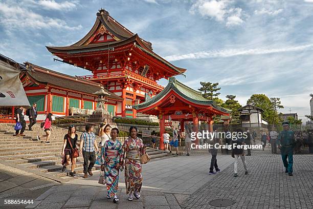 Tourists, some dressed in traditional Japanese kimono, wander around the main shrine at Fushimi Inari.