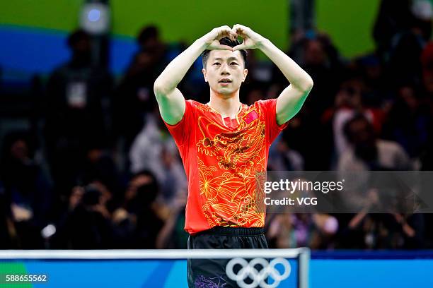 Ma Long of China makes the shape of a heart with his fingers after winning his match against Zhang Jike of China in Men's Singles Gold Medal Match on...