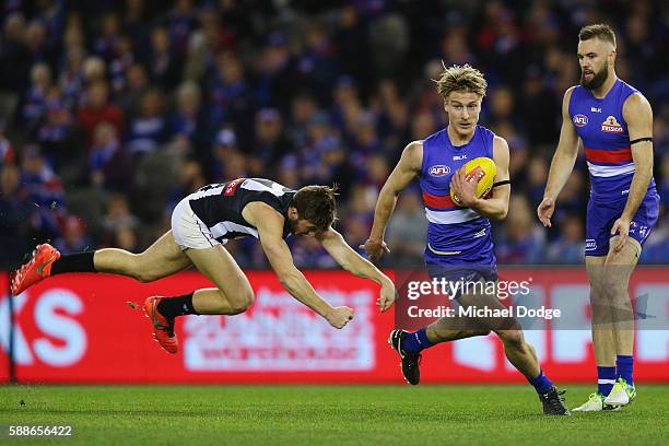 Shane Biggs of the Bulldogs runs with the ball away from Tom Phillips of the Magpies during the round 21 AFL match between the Western Bulldogs and...