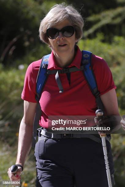 British Prime Minister Theresa May walks in a forest at the start of a summer holiday in the Alps in Switzerland on August 12, 2016 with her husband...