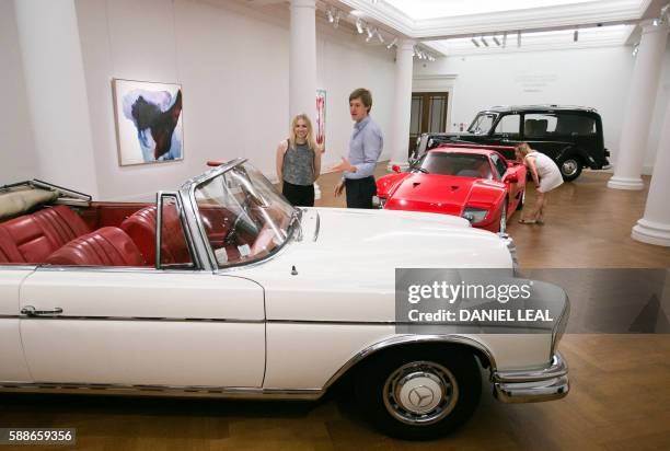 Sotheby's employees pose during a photo-call featuring late British musician John Lennon's 1956 Austin Princess Limousine hearse with an estimated...