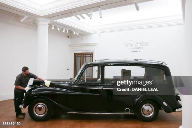 Sotheby's employee poses during a pre-sale photo-call featuring late British musician John Lennon's 1956 Austin Princess Limousine hearse with an...