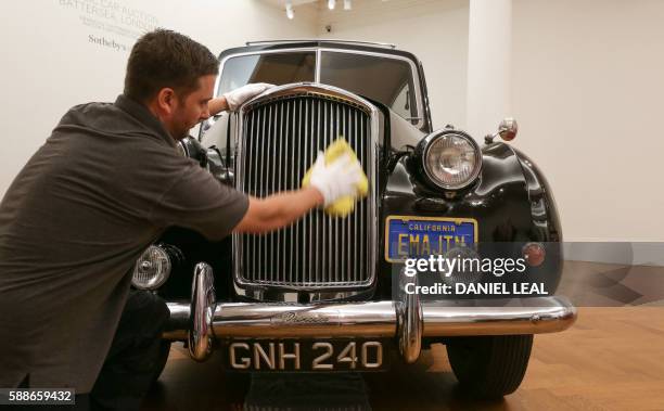 Sotheby's employee poses during a pre-sale photo-call featuring late British musician John Lennon's 1956 Austin Princess Limousine hearse with an...