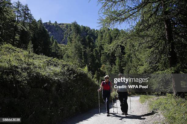 British Prime Minister Theresa May walks with her husband Philip John May while on summer holiday on August 12, 2016 in the Alps of Switzerland. The...