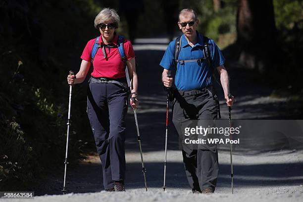 British Prime Minister Theresa May walks with her husband Philip John May while on summer holiday on August 12, 2016 in the Alps of Switzerland. The...
