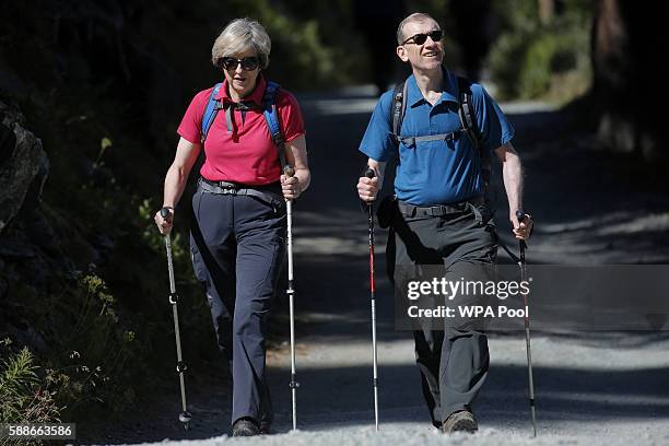 British Prime Minister Theresa May walks with her husband Philip John May while on summer holiday on August 12, 2016 in the Alps of Switzerland. The...