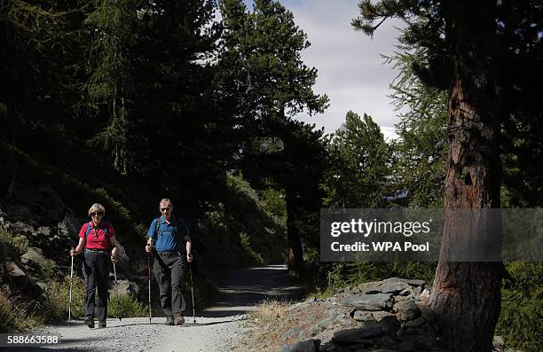 British Prime Minister Theresa May walks with her husband Philip John May while on summer holiday on August 12, 2016 in the Alps of Switzerland. The...