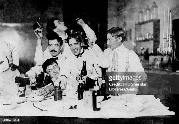 Group photograph of 1901 Johns Hopkins University PhDs drinking alcohol and partying in a chemistry lab, with one student drinking from a flask, one...