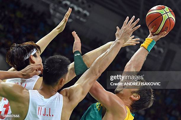 Australia's centre David Andersen takes a shot over China's centre Wang Zhelin and China's forward Yi Jianlian during a Men's round Group A...