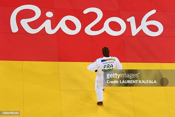 France's Teddy Riner walks on the tatami as he competes with Israel's Or Sasson during their men's +100kg judo contest semifinal A match of the Rio...