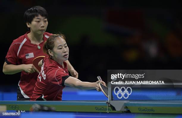 S Zheng Jiaqi hits a shot next to USA's Wu Yue in their women's team qualification round table tennis match against Germany at the Riocentro venue...