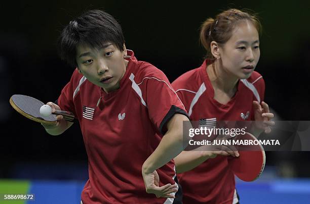 S Wu Yue hits a shot next to USA's Zheng Jiaqi in their women's team qualification round table tennis match against Germany at the Riocentro venue...