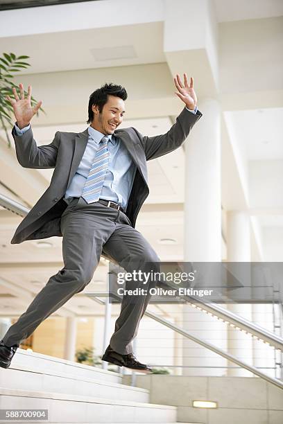 businessman sliding down stairway railing - railings ストックフォトと画像