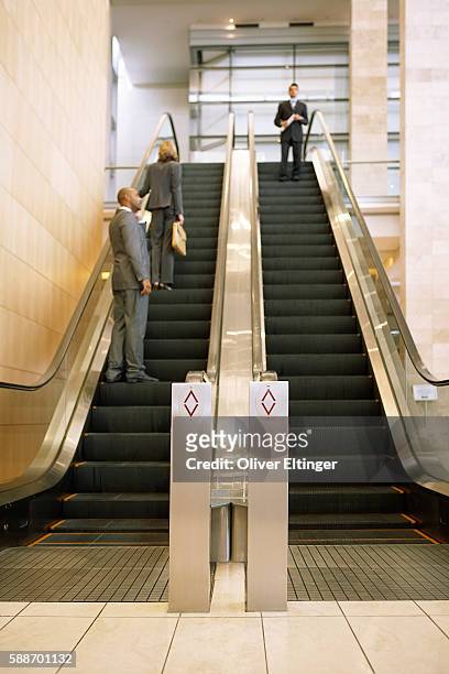 businesspeople on escalators - oliver eltinger stock-fotos und bilder