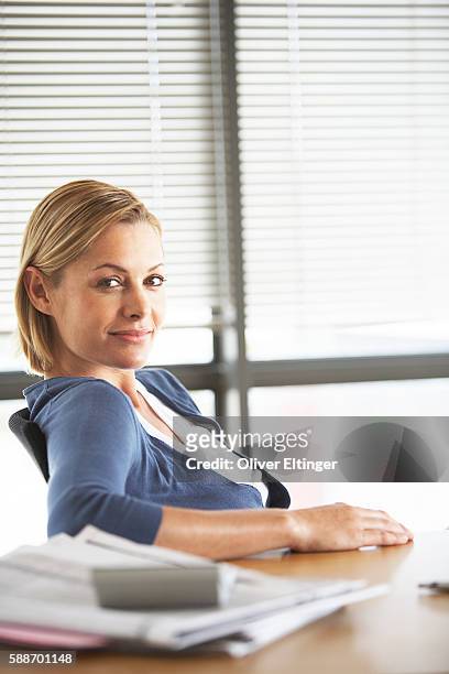 businesswoman sitting at desk - oliver eltinger stock-fotos und bilder