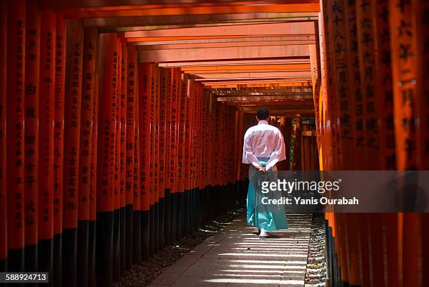 monk walking in fushimi inari shrine path of torii - fushimi inari schrein stock-fotos und bilder