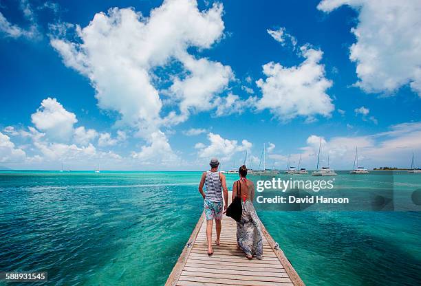 anegada island, british virgin islands, caribbean. a couple walks down a long dock surrounded by teal sea and blue sky. - blue sky friends stock pictures, royalty-free photos & images