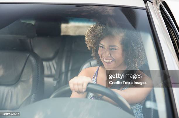 young woman smiling while driving car - windshield - fotografias e filmes do acervo