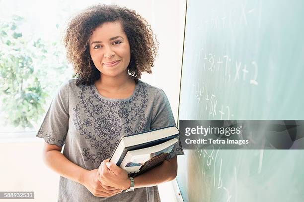 portrait of young woman holding books - tetra images teacher stock pictures, royalty-free photos & images