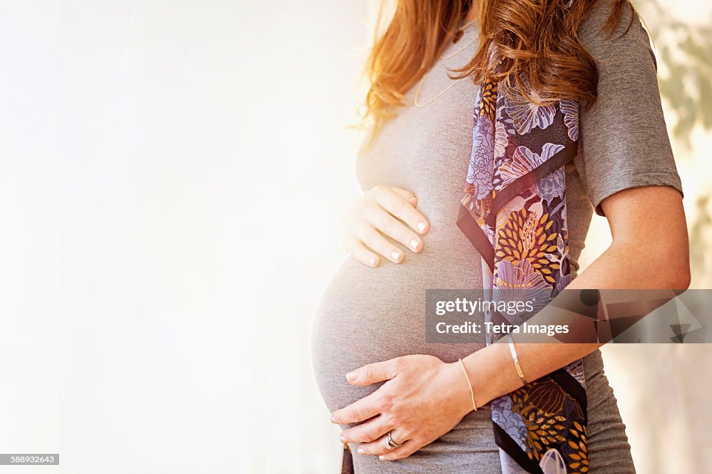 Mid-section of pregnant woman outdoors