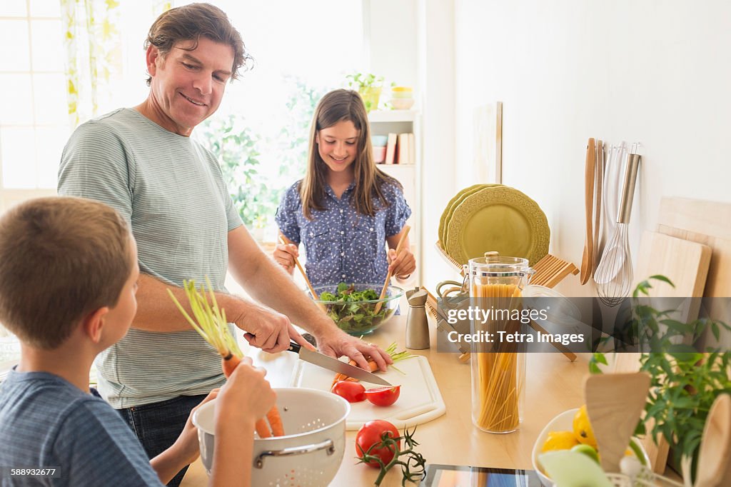 Children (8-9, 10-11) preparing food with their father