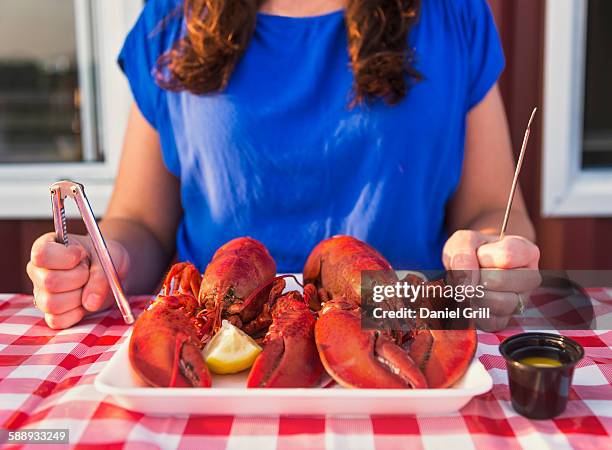 view of table with lobster meal and woman preparing to eat - lobster seafood stock pictures, royalty-free photos & images