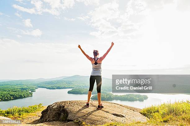 young woman standing on top of mountain with outstretched arms, rear view - tops woman stockfoto's en -beelden