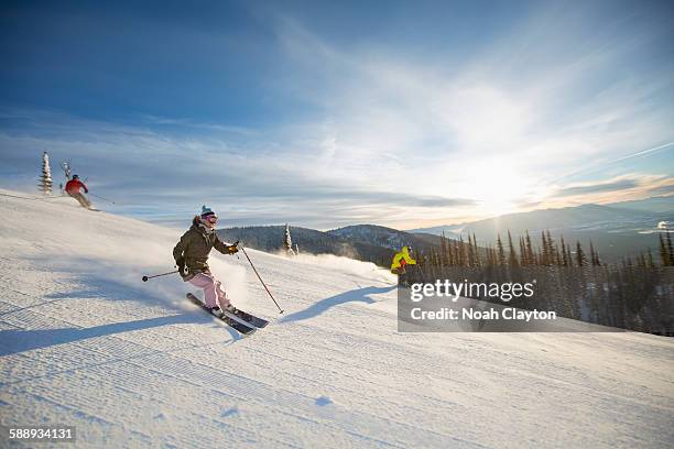 three people on ski slope at sunlight - whitefish montana stockfoto's en -beelden