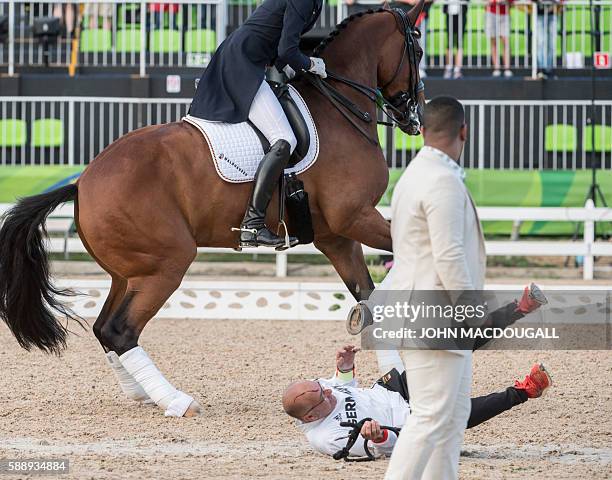 Groom falls to the ground after Germany's Sonke Rothenberg's horse Cosmo hit him in the head during the victory ceremony of the Equestrian's Dressage...