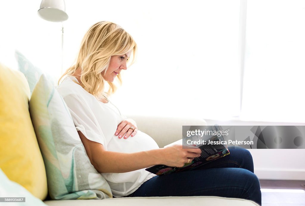 Pregnant woman reading book at home