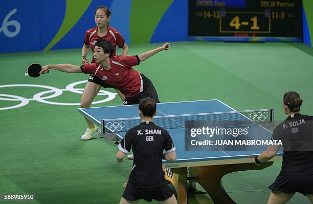 S Zheng Jiaqi watches her teammate Wu Yue hit a shot in the women's team qualification round table tennis match against Germany's Petrissa Solja and...
