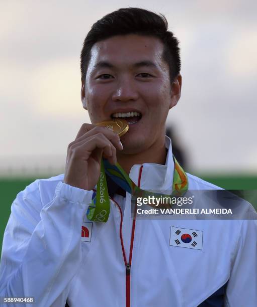 South Korea's gold medalist archer Ku Bonchan bites his medal on the podium during the medal ceremony of the men's individual competition at the...
