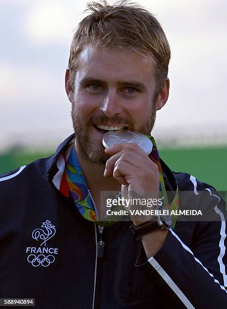 France's silver medalist archer Jean Lacques Valladont bites his medal on the podium during the medal ceremony of the men's individual competition at...