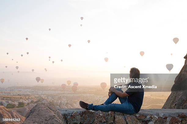 man watches hot air balloons rise above desert - hot air balloon people stock pictures, royalty-free photos & images